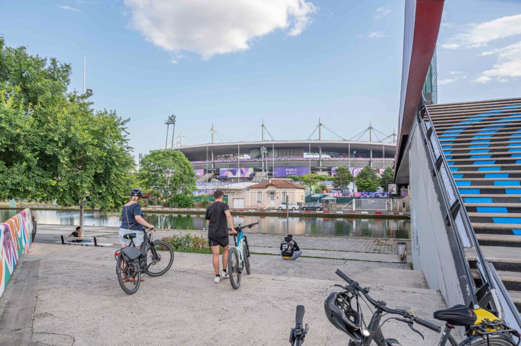 Cyclistes devant le stade de france avec des logos des JO